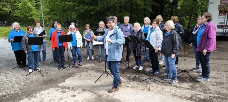 Sängerinnen und Sänger singen im Freien vor Notenpulten beim Waldfest